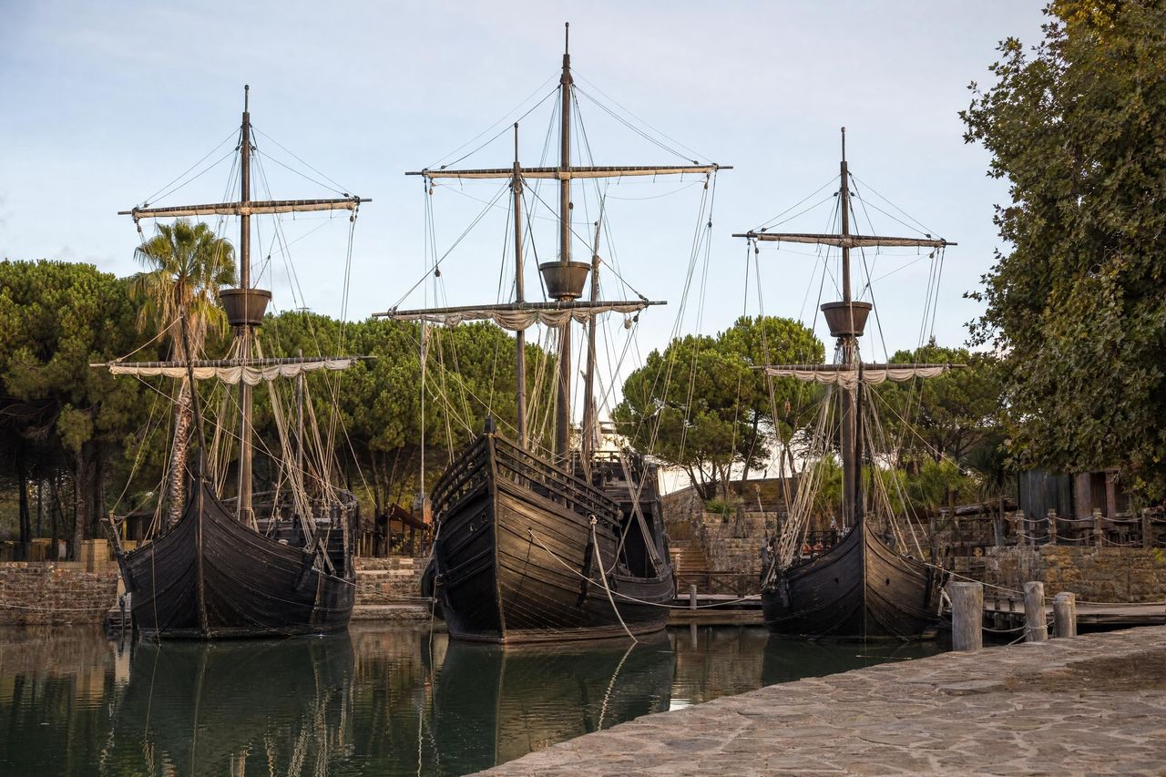 Réplicas a tamaño real de la Santa María, la Pinta y la Niña amarradas en el Muelle de las Carabelas, junto a Palos de la Frontera (imagen generada con AI)